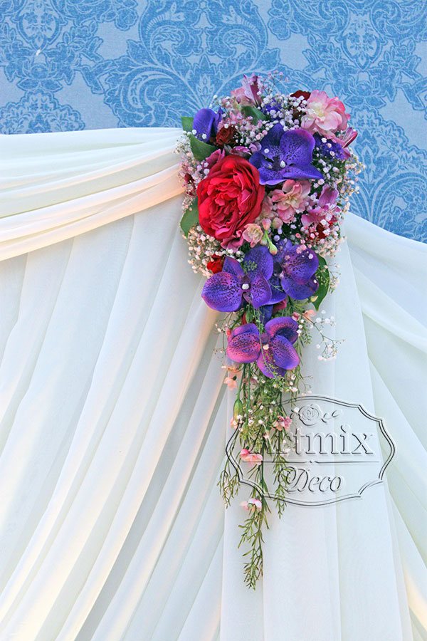 На фоне жениха и невесты цветочная композиция по форме