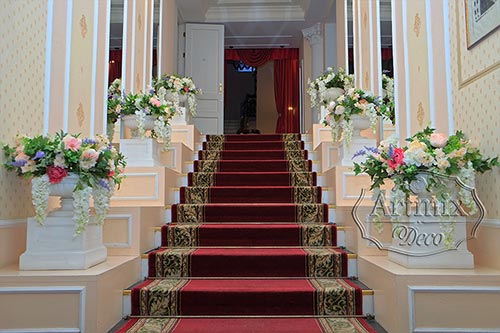 Гирлянда из зелени и вазы с цветами в свадебном оформлении лестнице