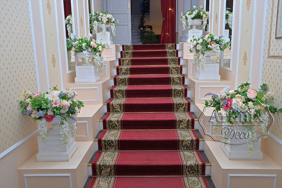 Гирлянда из зелени и вазы с цветами в свадебном оформлении лестнице