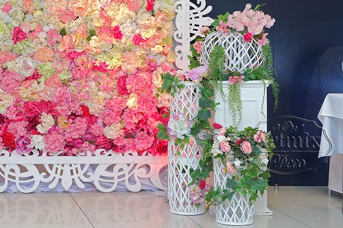 Белые металлические колонны с цветочными композициями