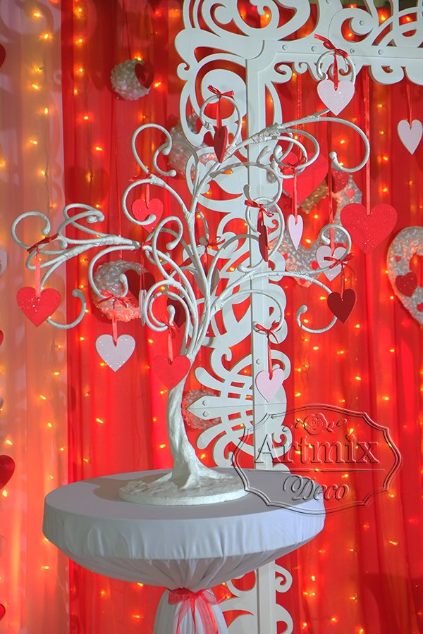 На высоком столе белое дерево с декором - сердцами