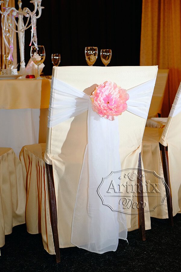Оформление стульев широкими лентами и декоративным цветком розового цвета