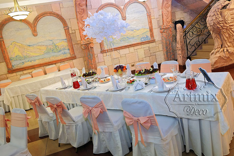 На столах гостей стоят высокие прозрачные вазы с декоративными веточками Гинкго Билоба