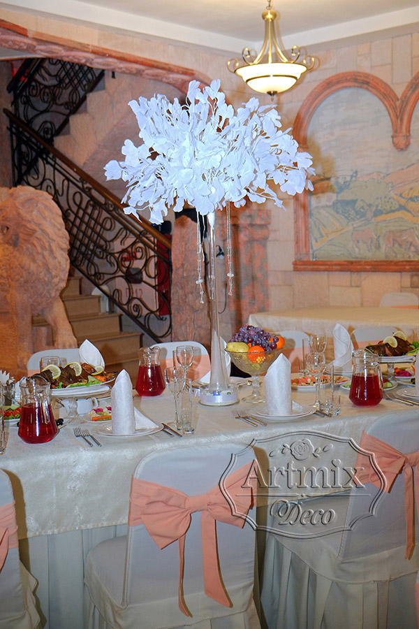 На столах гостей стоят высокие прозрачные вазы с декоративными веточками Гинкго Билоба