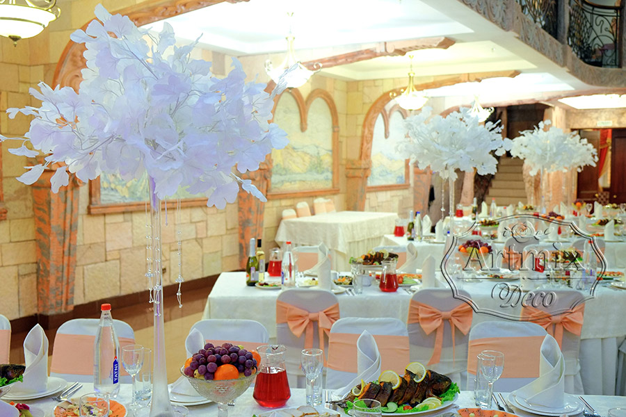 На свадебных столах гостей стоят высокие прозрачные вазы с декоративными веточками Гинкго Билоба