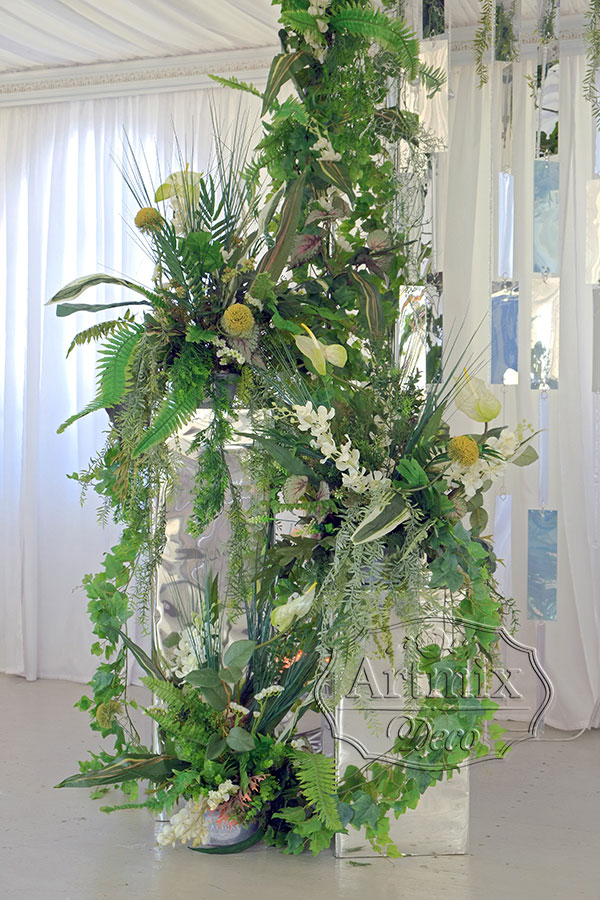 Зеркальные колонны оформлены в экзотическом стиле с добавлением цветов и листьев