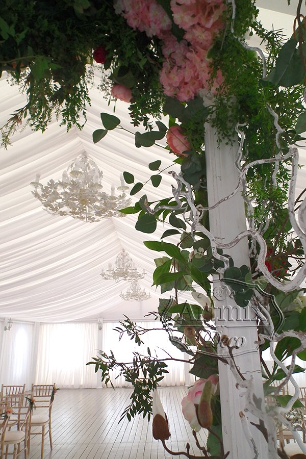Свадебная арка украшена гирляндами из зелени и вьющимися растениями