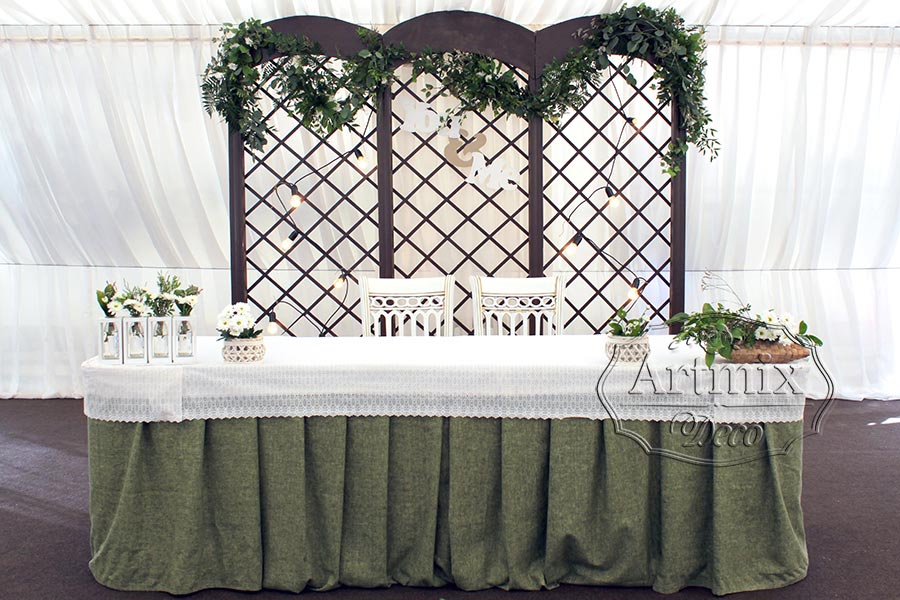 Свадебный стол жениха и невесты украшен фоном в виде арки - беседки