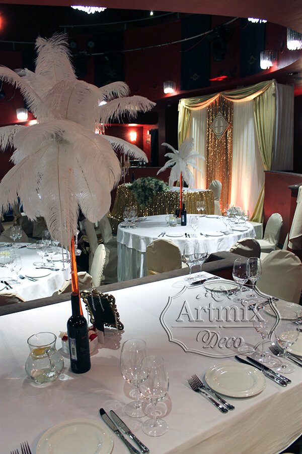 Страусиные перья в высоких вазах на столах гостей