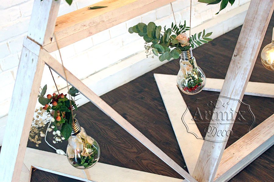 В оформлении фона у стола жениха и невесты - оригинальные флорариумы в виде ретро лампочек с цветами, ягодами и зеленью