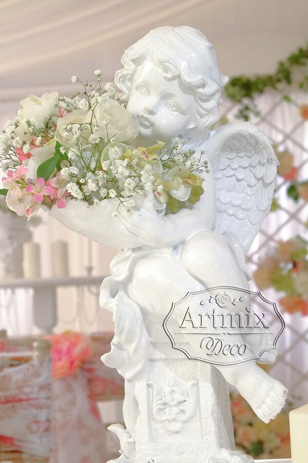Выездная свадьба украшена белыми тумбами, на которых стоят ангелы с цветами