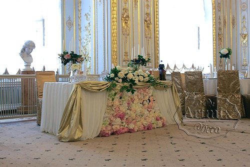 Свадебный президиум украшен золотой парчой и цветами 